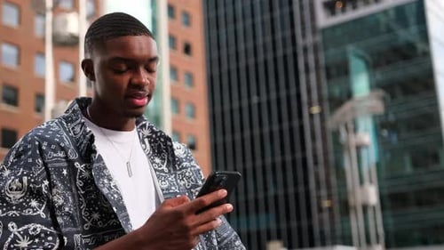 Young Man Uses Smartphone in Urban Setting