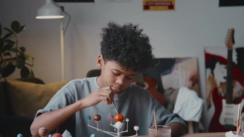 Boy Painting a Model Solar System at Home