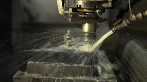 Iron milling in a cnc machine tools with water cooling. Machining of metal parts in the factory.