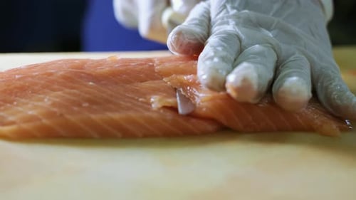Close up of Professional chef hand using fish fillet knife slice fresh orange salmon meat on cutting