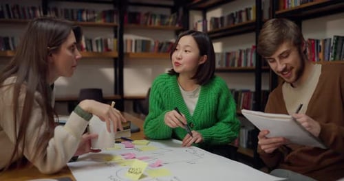 Une fille asiatique communique avec ses semblables tout en élaborant un grand plan sur une feuille de papier