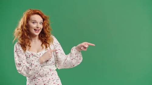 Glückliche lächelnde Frau präsentiert und zeigt etwas Isoliertes auf grünem Hintergrund Porträt von Pretty