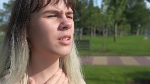 Young Woman Uses Inhaler in Green Park