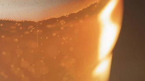 Nahaufnahme von Bierblasen, die an die Spitze eines gebogenen Bierglases steigen, mit Kopierraum