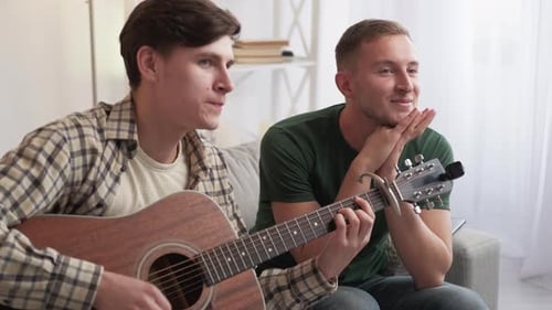 Young Adults Playing Guitar Together at Home