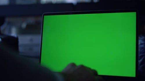 Unrecognized businessman typing business email on chroma key laptop at dark workplace