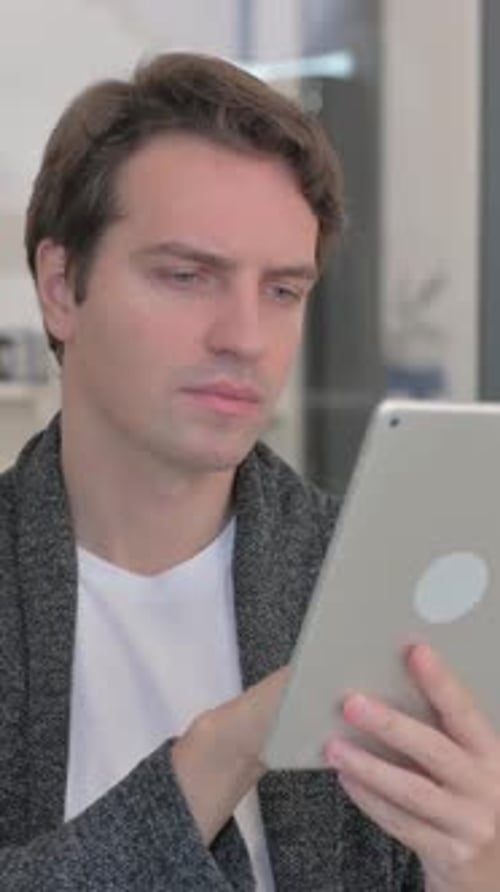 Young Adult Man Using Tablet Device Indoors