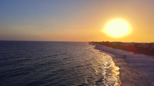 A cinematic flight above a powder white beach in the Florida Panhandle at sunset. A typical peaceful
