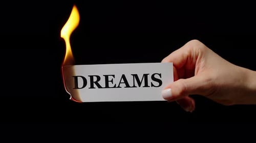 Hand Holding Burning Paper with the Word Dreams