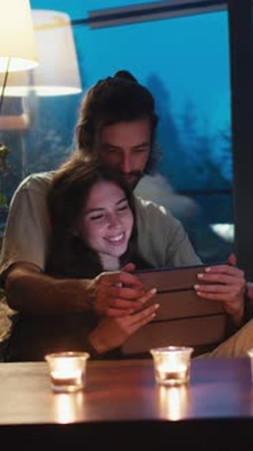 Romantic Couple Watching Tablet at Candlelit Table