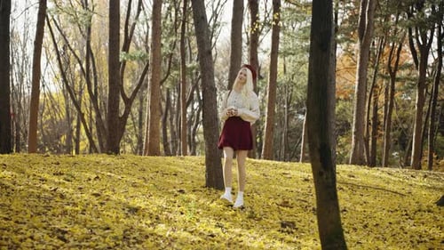 Blonde Woman Walking with Coffee Cup in Autumn Forest Park