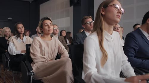 Crowd listens to woman speaker at business conference in modern auditorium