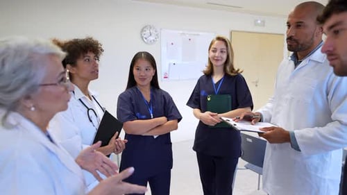 Medical Team Discussing Patient Charts in Hospital Corridor