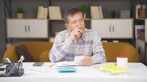 Man Reviews Finances at Home, Counting Cash