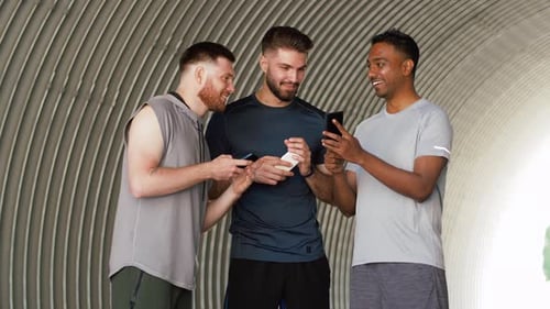 Three Young Men Looking at Phones Together