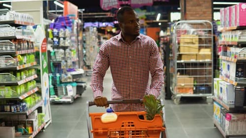 African American Man Walking with Shopping Trolley While Doing Shopping in Grocery Store