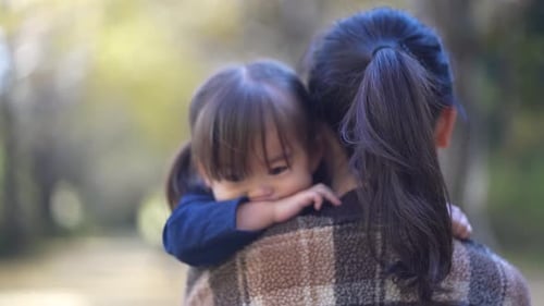 Little Girl Resting on Mother's Shoulder Outdoors