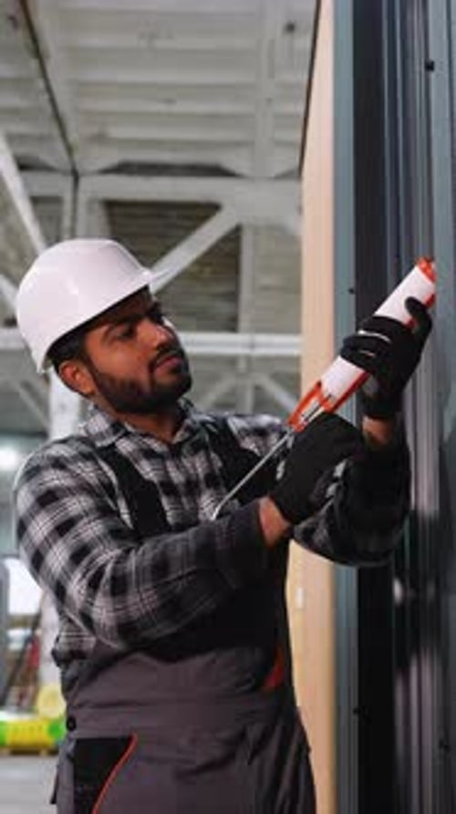 Trabajador de la construcción aplica sellador al panel de pared