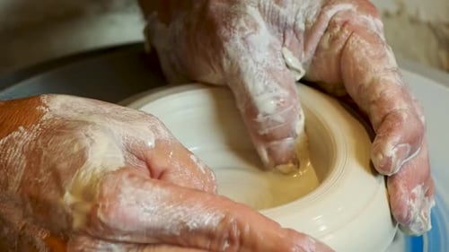 Close up of the potter's hand shaping and molding clay on a turning wheel .