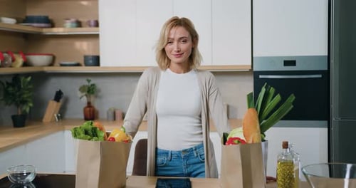 Portrait of woman chef wearing short smiling with joy at camera stand by kitchen near paper bag full