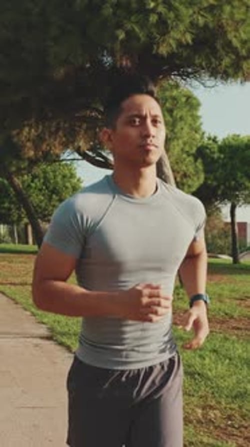 Young man running along the path in the park