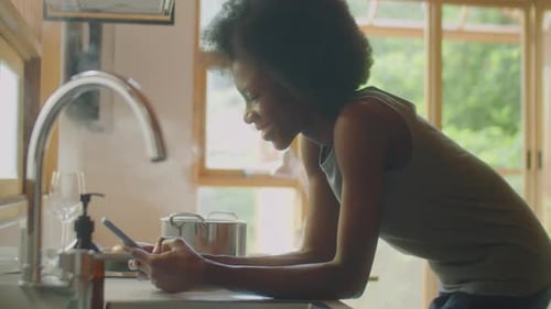Woman Using Smartphone in Bright Kitchen