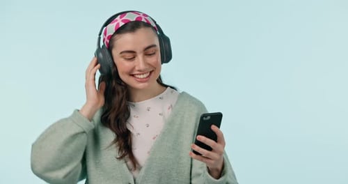 Studio music, phone and dancing happy woman listening, watch or streaming social network video