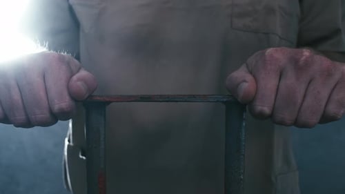 Extreme Nahaufnahme einer Parallaxenaufnahme der Hände eines Gefangenen, die sich an den Gittern seiner Zelle festhalten. Wenn die Kamera
