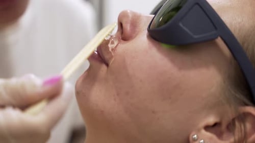 Close up shot of doctor puts special gel on female patient face before lazer hair removal