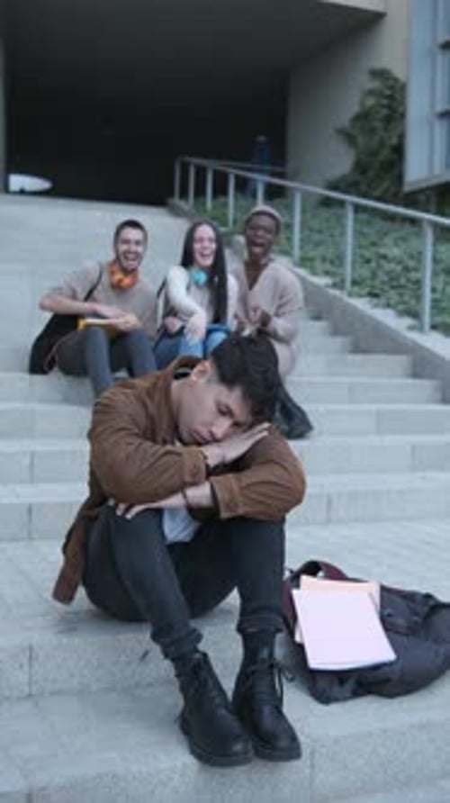 Group of Students Bulling a Latin Man Sitting on the Stairs Outdoors