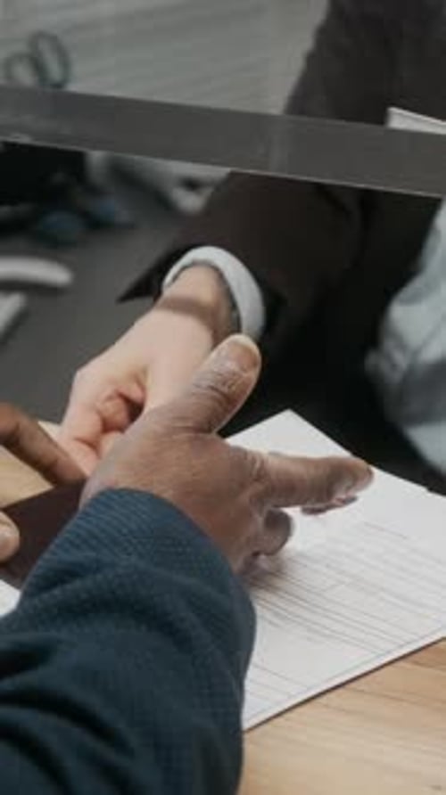 Vertical of Anonymous Black Man Submitting Paperwork at Visa Center