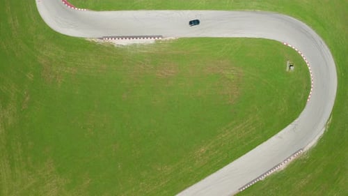 Single race car takes a sharp corner on race track. Topdown aerial view.