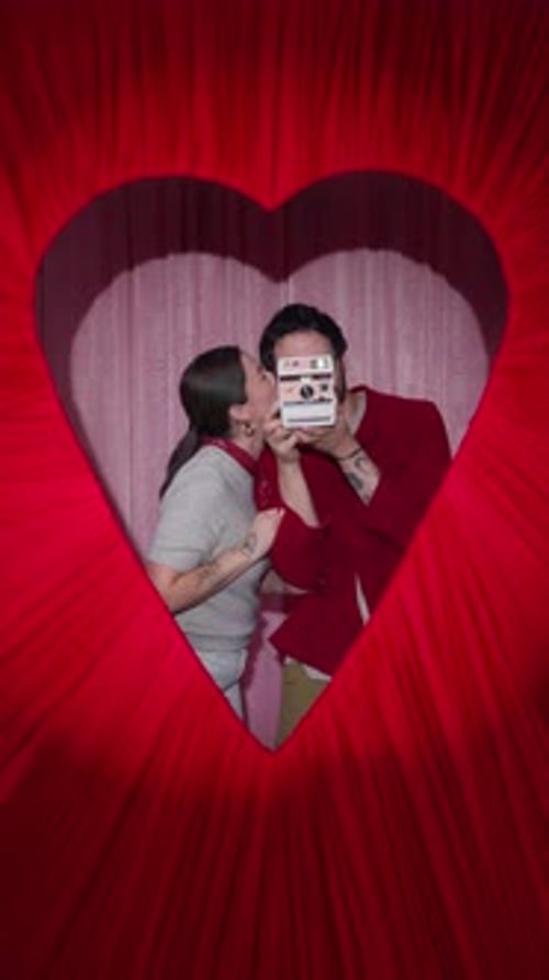 Latin Couple Taking Instant Photo in Heart Shaped Valentine Booth