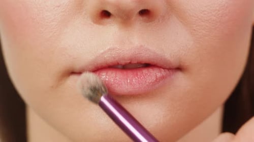 Schönheitsaufnahme einer Visagistin, die Foundation Bb Cream auf zuvor aufgetragene Feuchtigkeitscreme aufträgt