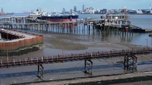 Crude oil tanker ship loading at refinery harbour terminal pipeline aerial view dolly right