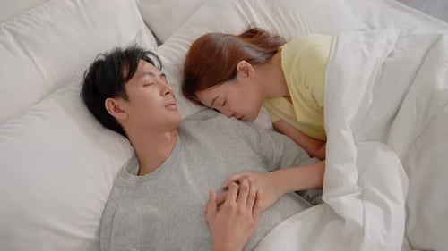 Affectionate Couple Sleeping and Holding Hands in Bed