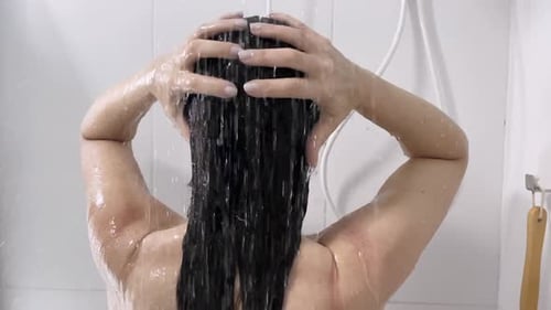 Woman washing long, dark hair in shower