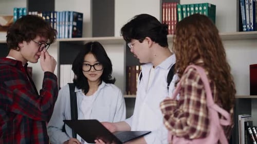 Verschiedene Schüler arbeiten mit Laptop in der Bibliothek zusammen