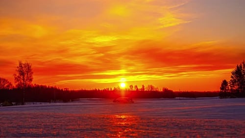 Timelapse of bright sun rising in golden sky over snowy landscape. Sky for copy space