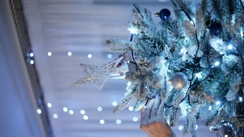 Woman Decorating Christmas Tree with Star Ornament