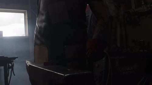 Blacksmith striking metal rod on an anvil in an artisan workshop