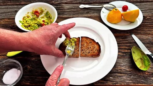 Man Prepares Avocado Toast on Wooden Table