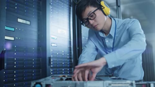 En el centro de datos moderno: un ingeniero de TI que lleva auriculares protectores instala un nuevo hardware para Serv