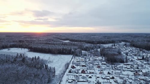 Enjoying a Winter Sunset Casting a Warm Glow Over a SnowCovered Village and Forest with a Blurry