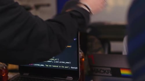 Hacker an Laptops mit Computercode während des Hackathons 2024