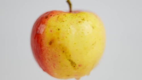 Nahaufnahme Nasser roter gelber Apfel, der sich in Zeitlupe auf weißem Hintergrund dreht Leckeres köstliches Vitamin