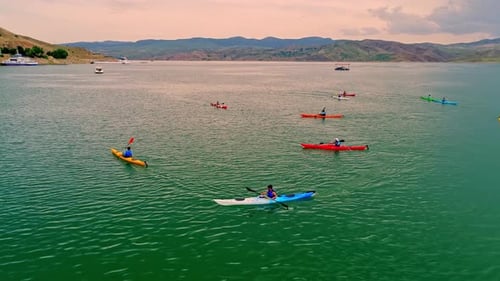 Kayakers Paddling on Lake Surrounded by Mountains