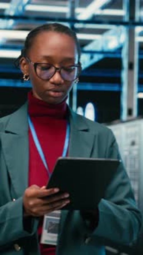 Vertical Video Female Engineer Walks in Data Center Using Tablet and AR Tech to Monitor Errors