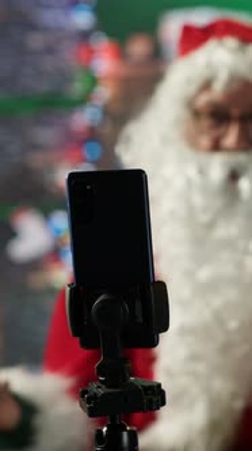 Vertical Video Father Christmas Recording a Blog Live on Smartphone in His Festive Log Cabin