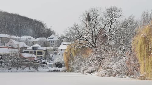 A quiet neighborhood in Prague is transformed by snow. Trees and houses covered in white surround a